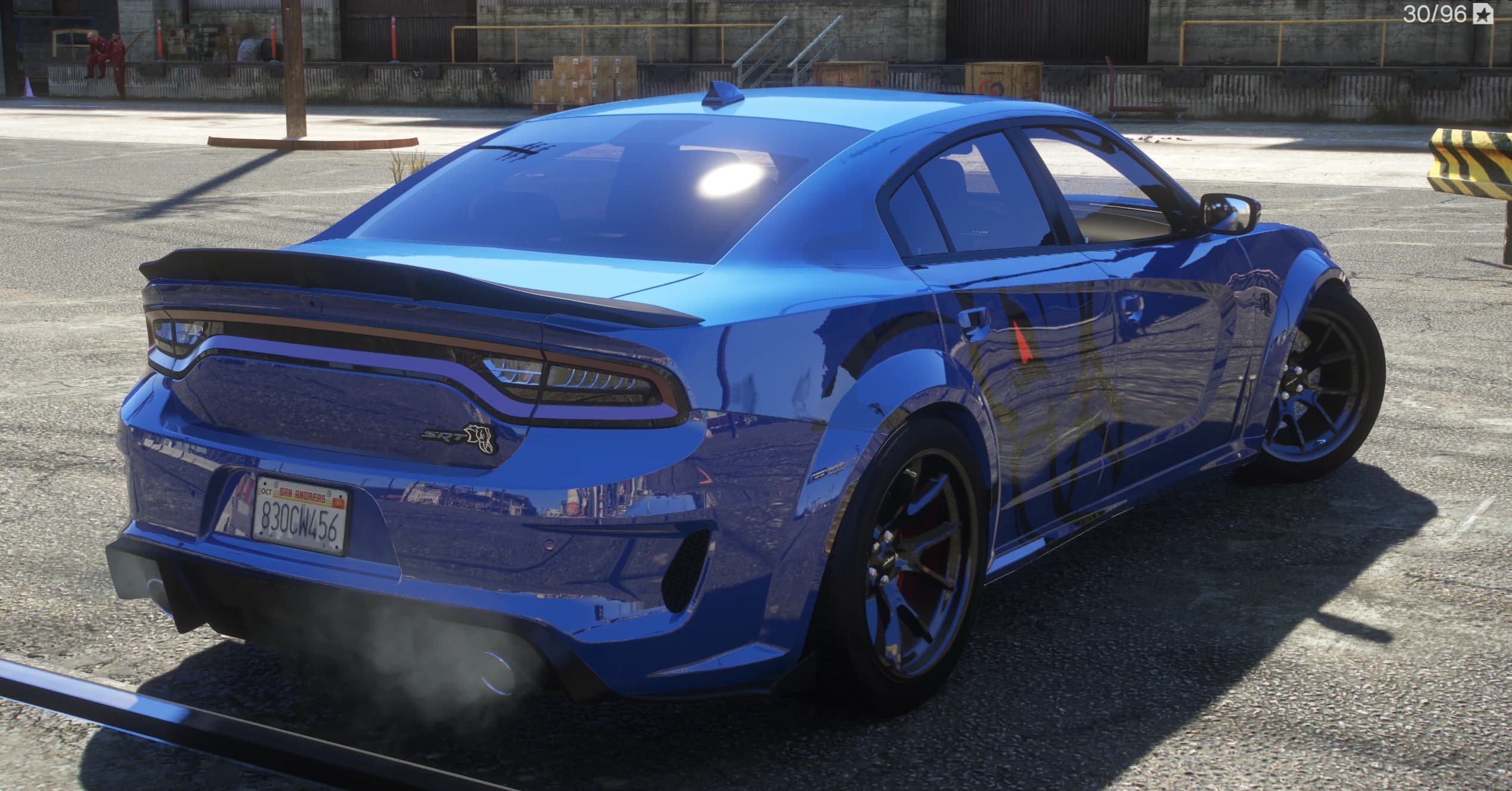 Tres cuartos trasero del Charger azul con la barra de luces LED de ancho completo, el emblema SRT Hellcat, el alerón tipo ducktail y humo de escape, con una matrícula de San Andreas 830CW456 sobre las aletas widebody