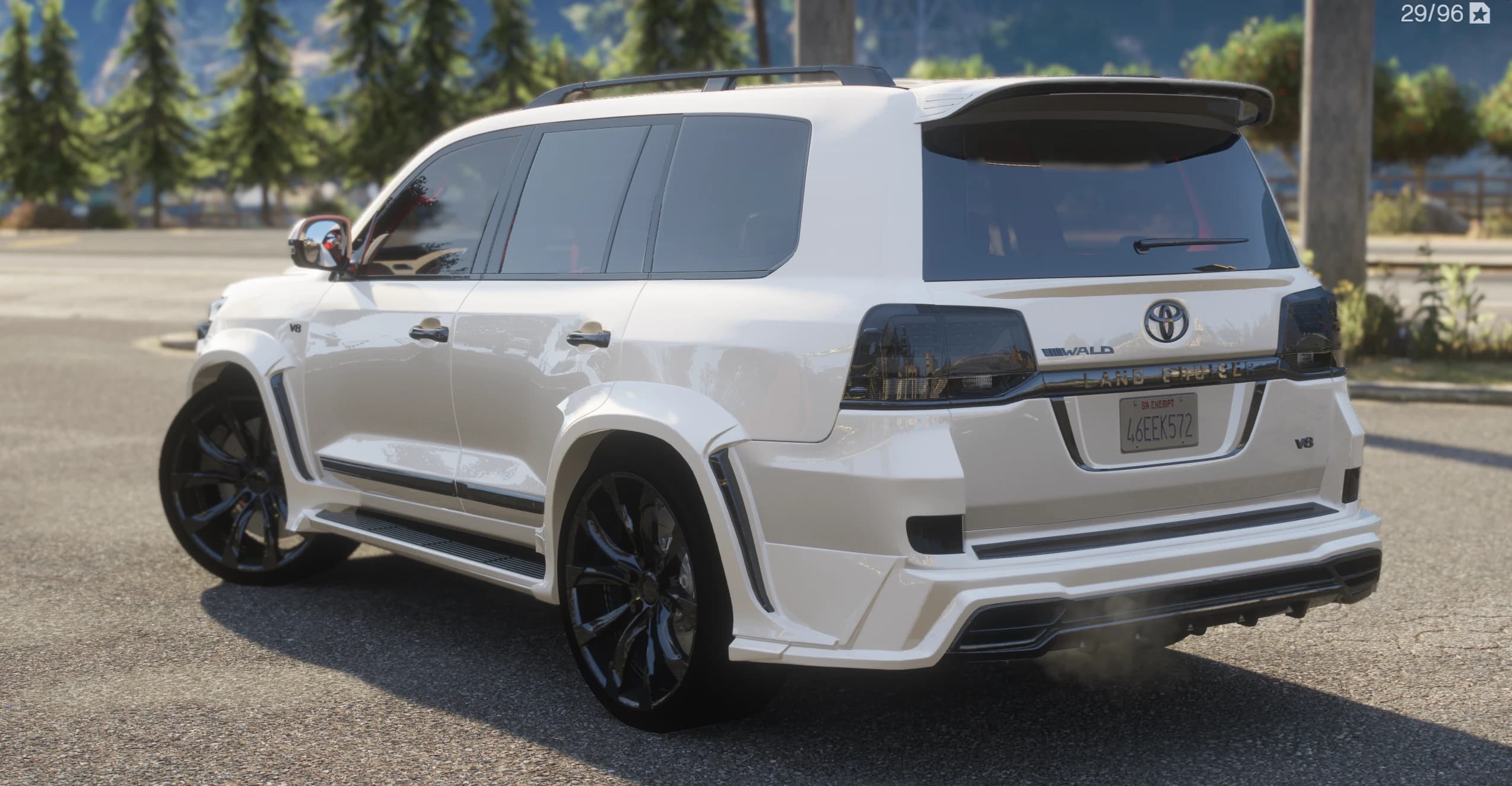 Tres cuartos trasero del Land Cruiser blanco con el rótulo LAND CRUISER, las insignias WALD y V8, el alerón de techo y las llantas negras