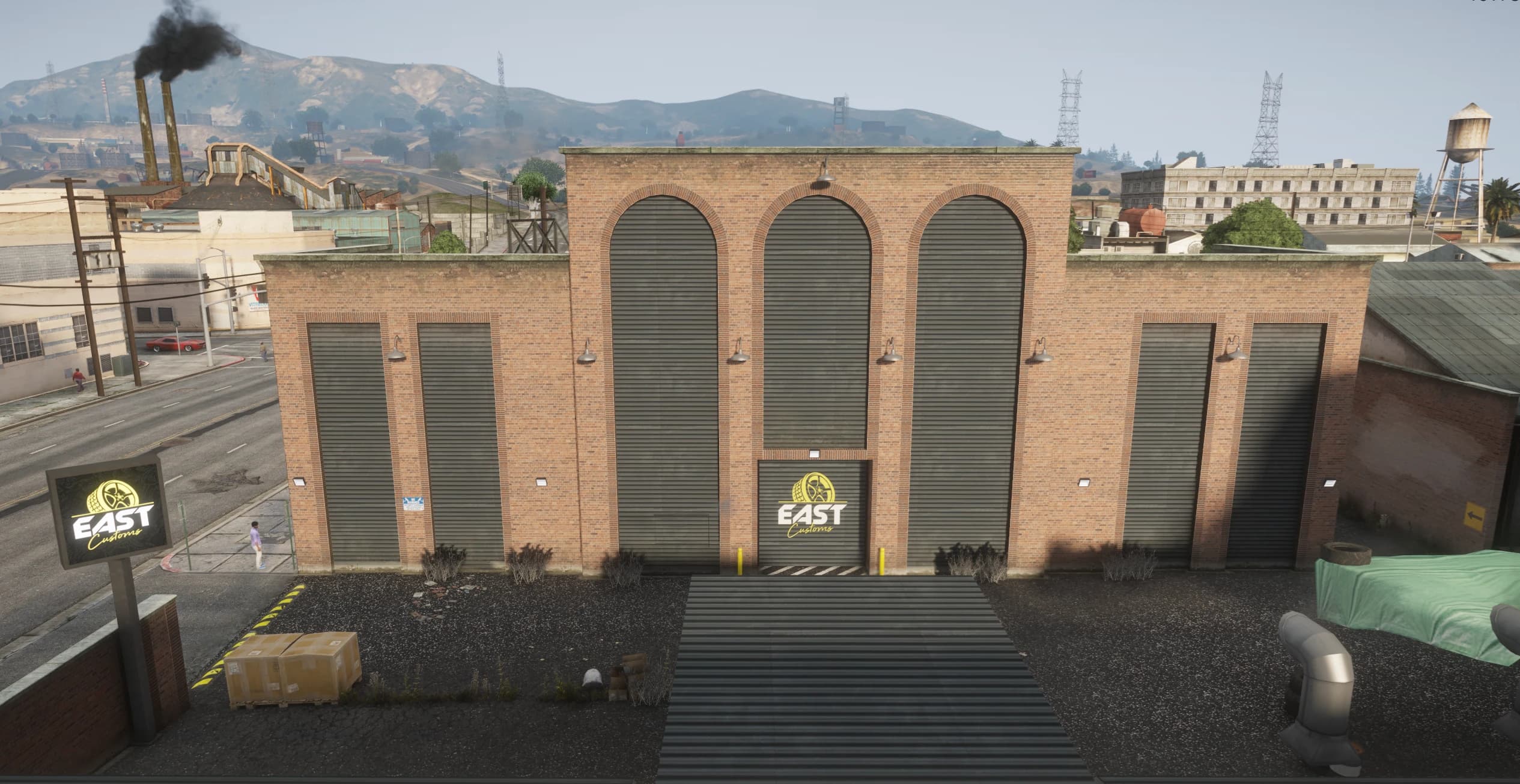 Fachada a la calle del edificio de ladrillo EAST Customs con sus portones de arco y los rótulos del logo