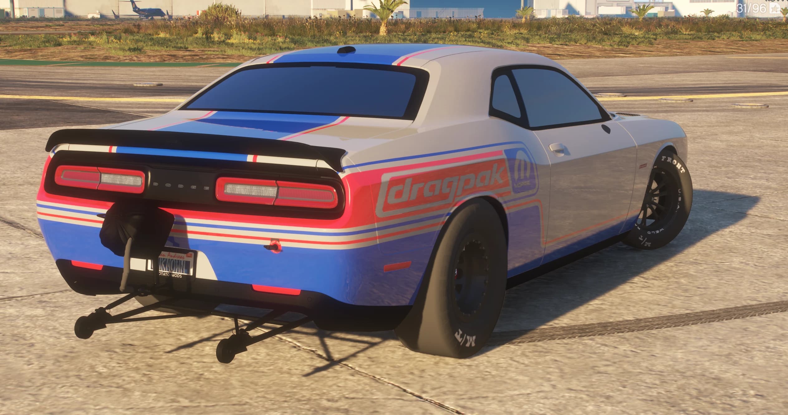 Vista trasera en tres cuartos con las barras de wheelie, el paquete del paracaídas, los vinilos dragpak y Mopar en la aleta y la banda de pilotos DODGE