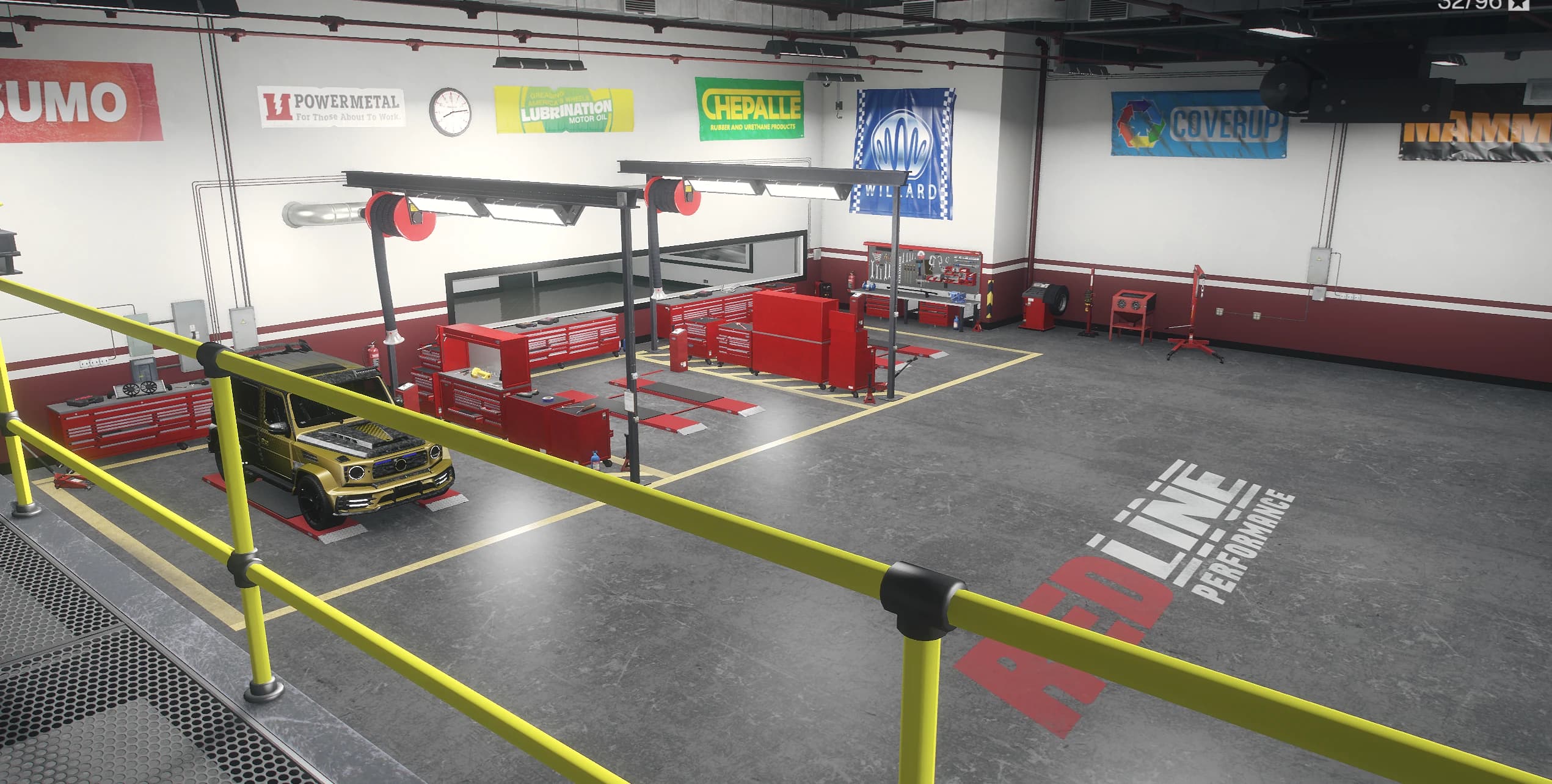 Interior del taller con dos bahías de trabajo, armarios de herramientas rojos, pancartas de patrocinadores y un todoterreno dorado en la plataforma