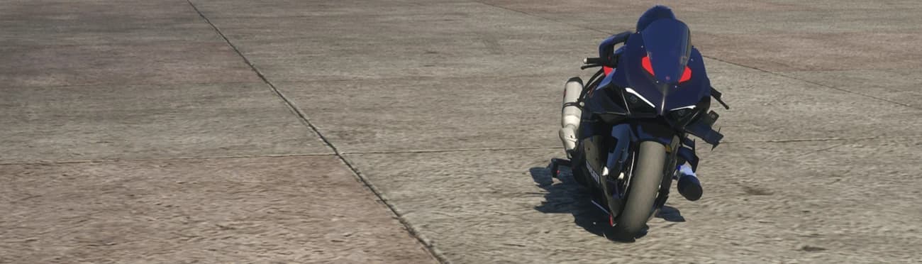 Vista frontal lejana de la Ducati V4 de drag oscura aparcada sola en la pista vacía de un aeródromo