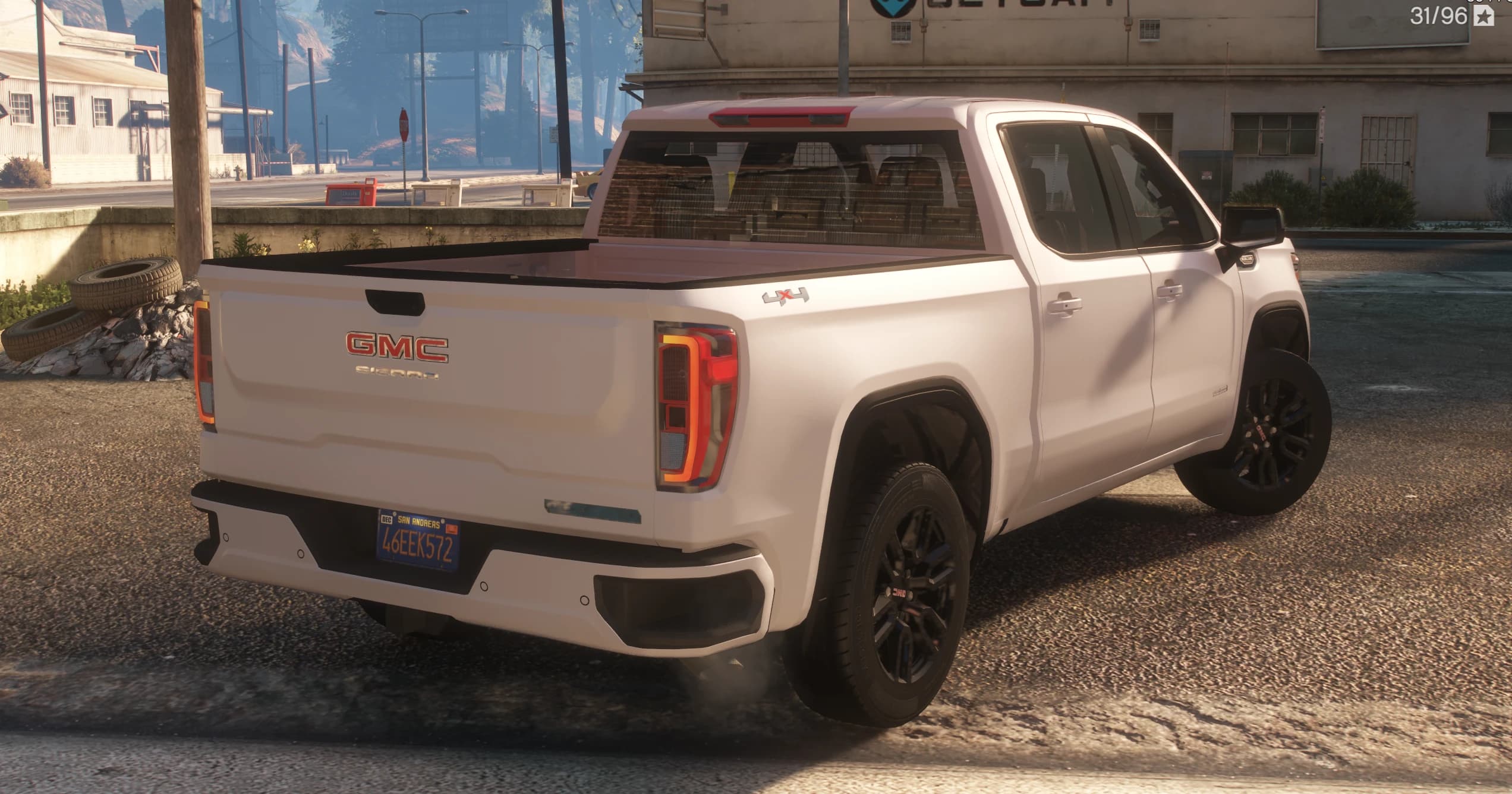 Vista trasera en tres cuartos con las letras GMC y Sierra en el portón, pilotos en forma de C y la insignia 4x4 en la caja