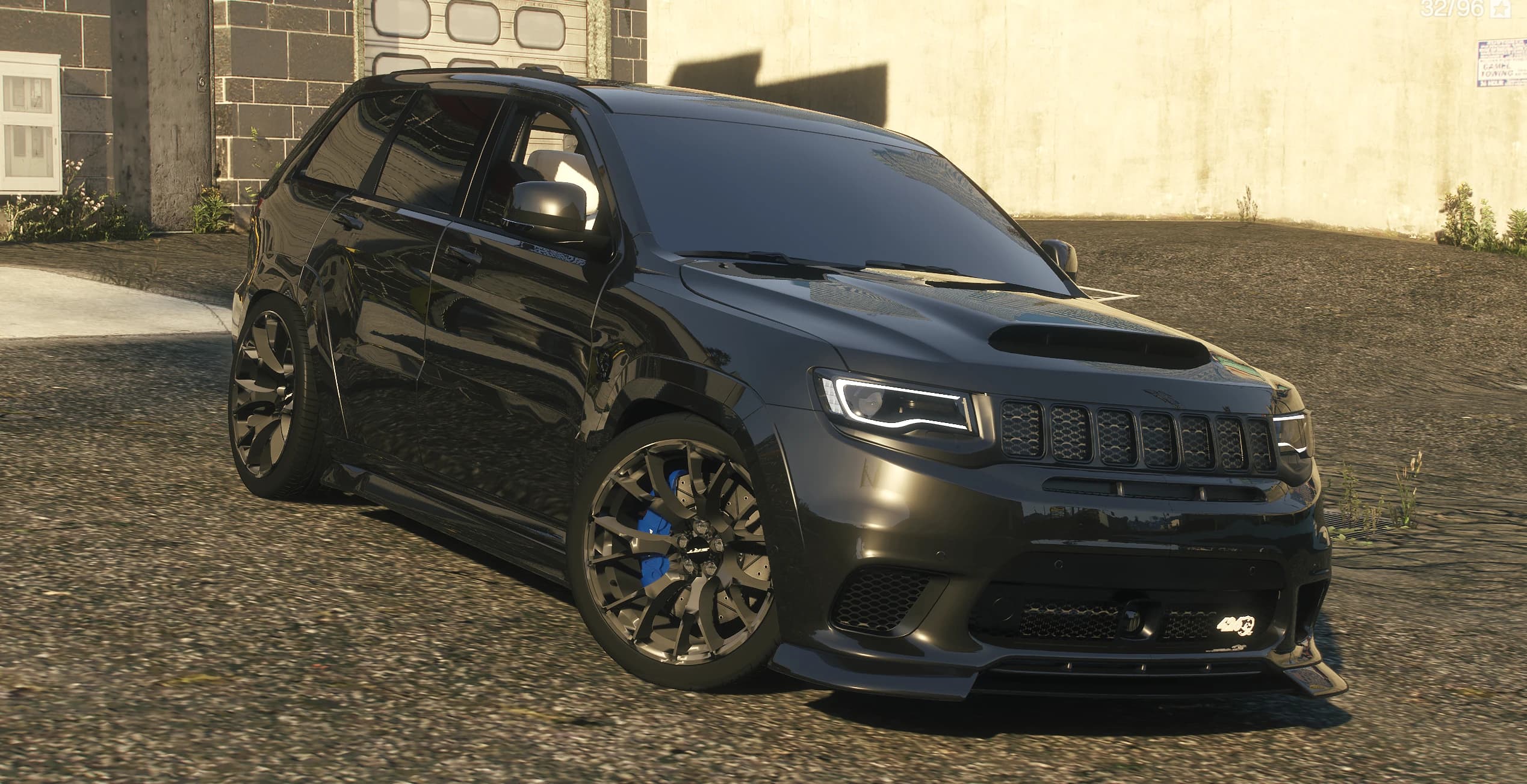 Vista frontal en tres cuartos del Trackhawk negro con la toma del capó, llantas negras y pinzas azules