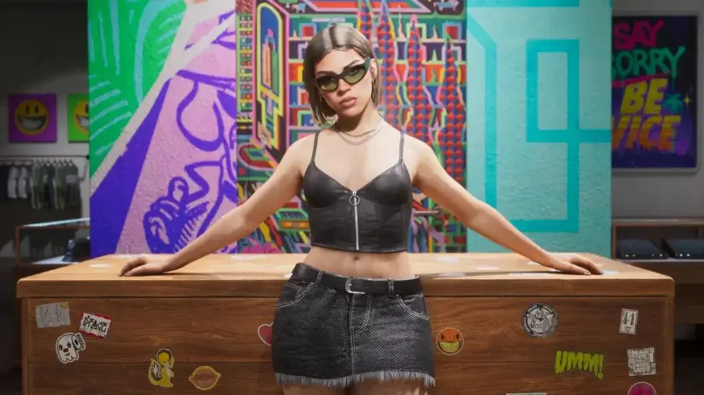 Lucia con gafas de sol apoyada de espaldas en el mostrador de madera de una tienda, cubierto de pegatinas, con percheros de ropa a la izquierda, vitrinas de cristal a la derecha y murales de colores llenando la pared del fondo